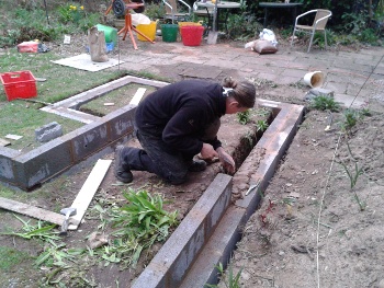 Alex constructing the second course of breeze blocks for the raised vegetable bed.